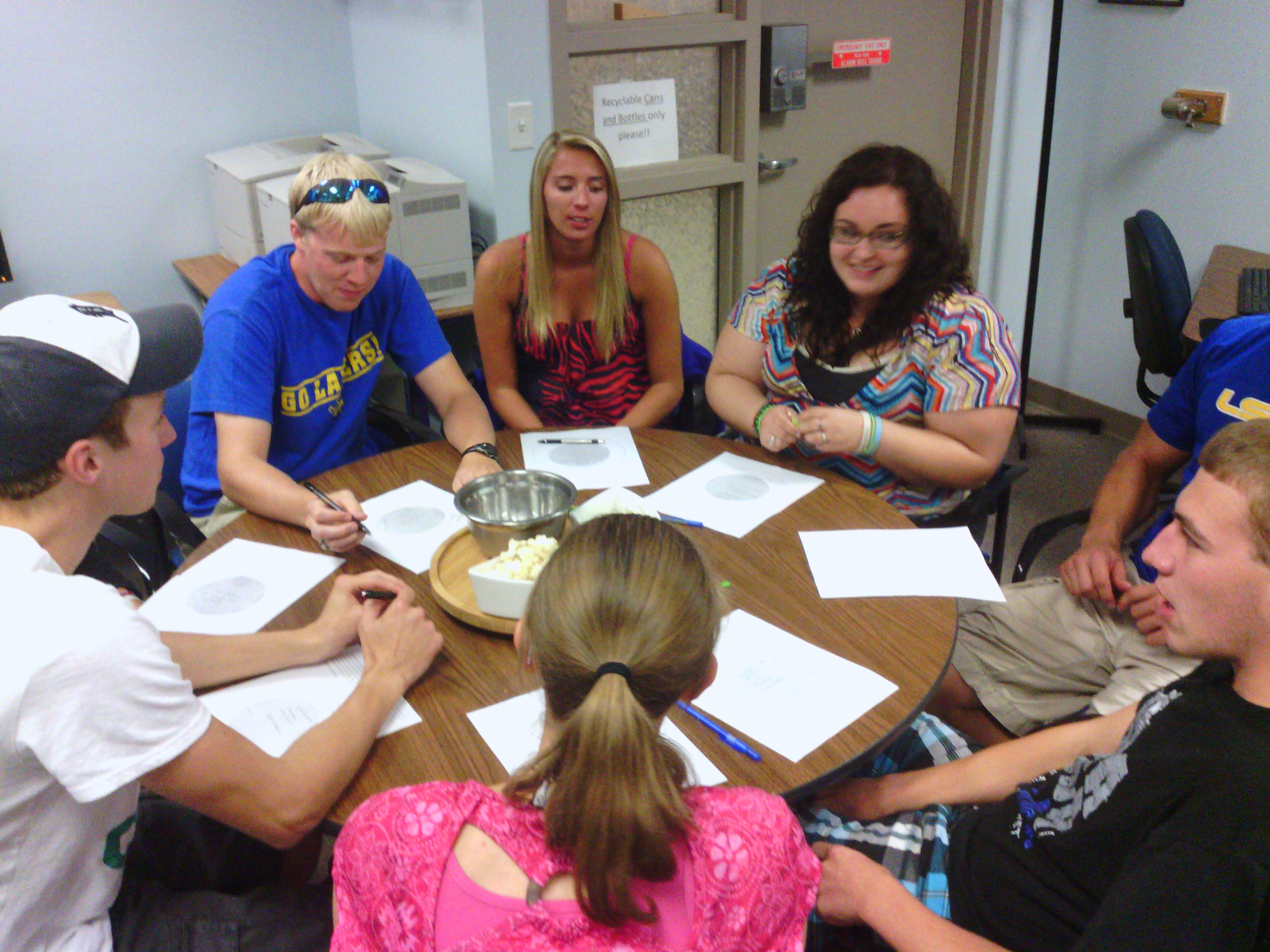 Group of students sitting around a round table with papers in front of them