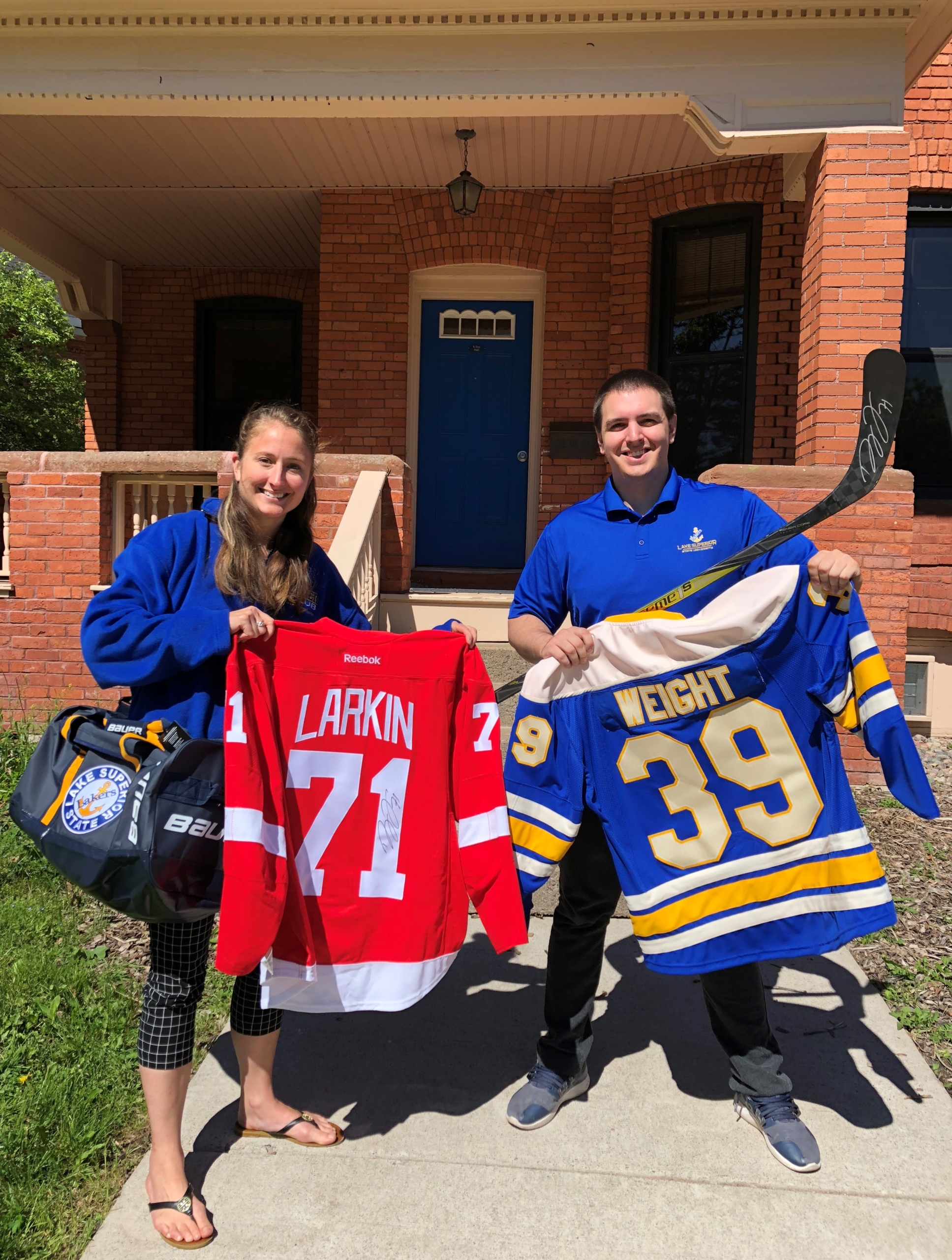 LSSU Foundation staff members pose with items available for auction during the online and live auctions as part of the Lake State Classic.